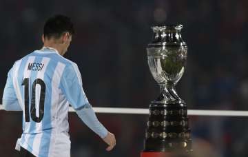Lionel Messi walking past the Copa America Trophy.