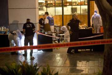 Israeli police officers examine the scene of a shooting attack in Tel Aviv