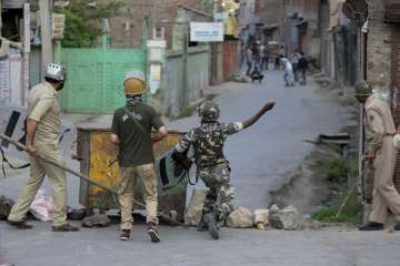 Security personnel clash with protesters in a street in Srinagar