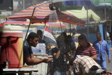 People cool off from the summer heat by using an open air shower in Baghdad