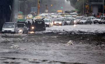 Vehicles make way through  waterlogged road in Delhi on Wednesday