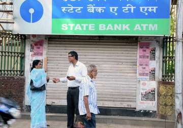 People stand as an ATM closed for the day due to demonetization 