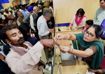 A bank employee applys ink to a customer on exchange of Rs 500, Rs 1,000 notes