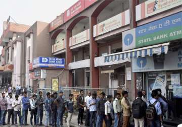 People stand in a long queue to withdraw money at an ATM in Patna 