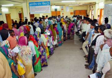 People stand in queue at a SBI branch to exchange their currency 