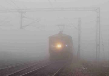 A train moves slowly amid a thick blanket of fog on a cold morning in Delhi