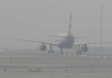 A British Airways plane is seen through dense fog at Heathrow Airport