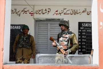 A jawan stand guard outside a polling station for Srinagar LS bypolls