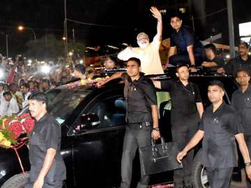 PM Modi waves at people during a road show in Surat on Sunday