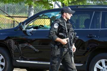 A policeman walks past a car with window damaged at the scene of shooting