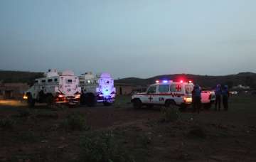 UN armored personnel vehicles stationed with an ambulance outside attack site