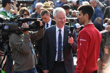 Novak Djokovic of Serbia is interviewed by John McEnroe following his victory