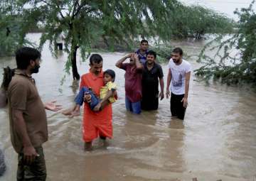 People wade through floodwaters after heavy rainfall in Gujarat's Morbi district