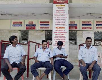 Guards sitting near the ticket counter of a closed cinema hall in Chennai