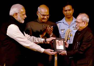 Modi handing a book to Mukherjee as Ram Nath Kovind looks on 