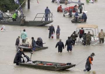 People and rescue boats line a street at the east Sam Houston Tollway