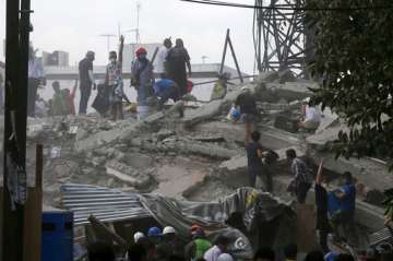 Volunteers search a building that collapsed after an earthquake.