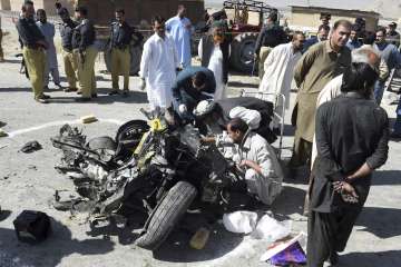Pakistani officials examine a wreckage of a vehicle following a car bomb attack on a police truck in Quetta