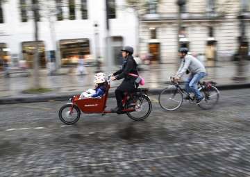 Pice - A woman and a man ride their bicycles on the Champs Elysees avenue