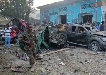 Somali soldier walk near wreckage of vehicles after a car bomb was detonated in Mogadishu