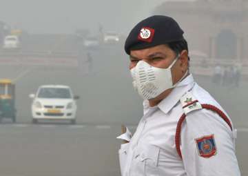 A traffic policeman, wearing an anti-pollution mask, mans traffic amid smog and air pollution which continues to be above dangerous level, at Vijay Chowk