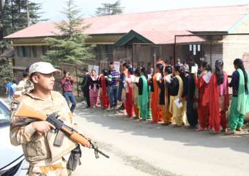 Voters wait in a queue to cast their votes during Himachal Pradesh assembly elections at a polling booth in Shimla