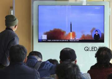 People watch a TV screen showing file footage of North Korea’s missile launch at Seoul Railway Station in Seoul