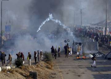 Protesters hurls back a tear gas shell fired by police during a clash in Islamabad