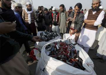 Supporters of a radical religious party gather around a pile of empty tear gas canisters and rubble bullets fired by police during clash in Islamabad