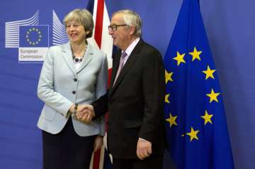 British PM Theresa May, left, is greeted by European Commission President Jean-Claude Juncker ahead of a meeting at EU headquarters in Brussels on Friday, Dec. 8, 2017.
