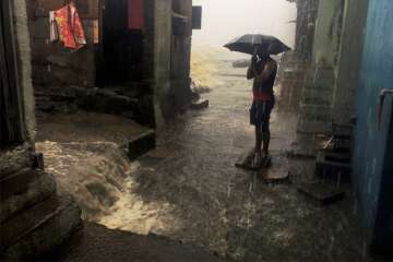 A man stand with an umbrella in a street amid heavy showers triggered by cyclone Ockhi.