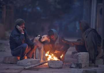 People sitting around a bonfire to warm themselves during a cold morning in old Delhi on Sunday