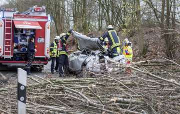 Rescue workers are busy at the site where a car was hit by a falling tree during a storm in Moers, western Germany, Thursday, Jan. 18, 2018. The driver was seriously injured in the accident. 
