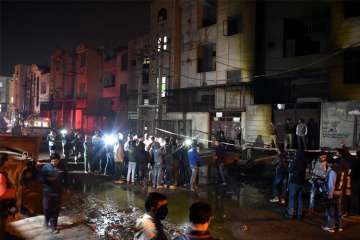 Fire fighters and media outside the two-storey cracker factory which caught fire in north Delhi's Bawana Industrial Area on Saturday. At least 17 people have died in the fire.