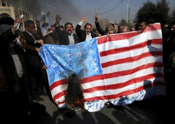 Iranian worshippers chant slogans while they burn a representation of US flag during a rally against anti-government protestors after the Friday prayer ceremony in Tehran on January 5