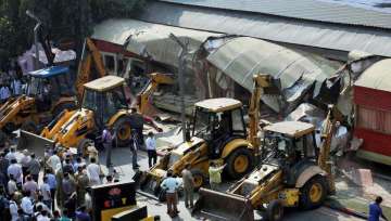 Onlookers gather around as BMC bulldozers take down illegally constructed eateries in the Kamala Mills compound following a fire incident in Mumbai.(PTI)
The city civic body continued to raze unauthorised structures of restaurants, hotels and other food joints for the third day today, after a fire i