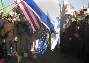 In this photo provided by Tasnim News Agency, Iranian demonstrators burn representations of U.S. and Israeli flags in a pro-government rally in the northeastern city of Mashhad, Iran