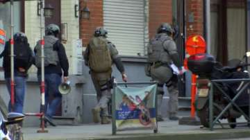 Belgium security personnel enter a building in Brussels in this image taken from TV Thursday Feb. 22, 2018. Belgian police have sealed off part of a Brussels suburb amid media reports that an armed man could be at large.