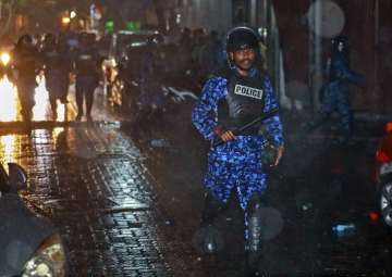 A Maldives policeman charges with baton towards protesters after the government declared a 15-day state of emergency in Male, Maldives, early Tuesday, Feb. 6, 2018.