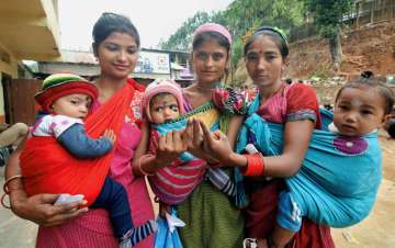 Women holding children, show their ink-marked fingers after casting their votes for the state Assembly elections, at a polling station at Byrnihat, Meghalaya on Tuesday