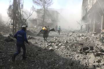 A Syrian monitoring group and paramedics say government shelling and airstrikes on rebel-held suburbs of the capital, Damascus, killed at least 98 people on Monday. (Syrian Civil Defense White Helmets via AP)