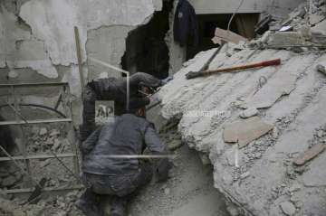 In this photo released on February 21, 2018 which was provided by the Syrian Civil Defense group known as the White Helmets, shows a member of the Syrian Civil Defense group, searches for victims under the rubble of a destroyed house that attacked by Syrian government forces airstrike, in Ghouta.
