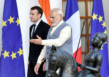 Prime Minister Narendra Modi walks with French President Emmanuel Macron as they arrive for a meeting at Hyderabad House in New Delhi on Saturday.