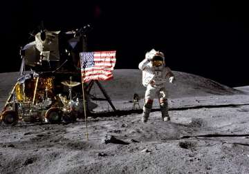 Astronaut leaping on lunar surface near landing vehicle and flag. File Photo
