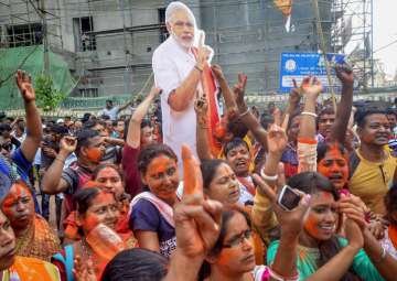 BJP supporters hold up a placard of Prime Minister Narendra Modi after party's victory in Tripura Assembly elections results in Agartala on Saturday.