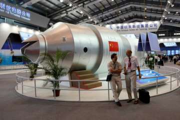 In this Nov 16, 2010 file photo, visitors sit beside a model of China’s Tiangong-1 space station at the 8th China International Aviation and Aerospace Exhibition in Zhuhai in southern China’s Guangdong Province.