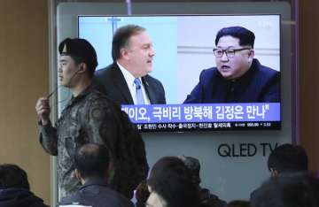 A South Korean army soldier passes by a TV screen showing file footage of CIA Director Mike Pompeo, left, and North Korean leader Kim Jong Un during a news program at the Seoul Railway Station in Seoul, South Korea, Wednesday