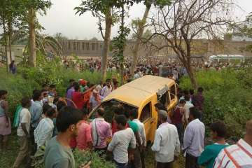 People gather around the mangled school van after it collided with a moving train in Kushinagar, Uttar Pradesh, on Thursday morning. 