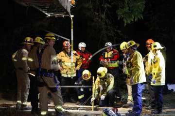 Firefighters search for a 13-year-old boy in a hole near the LA River at the 134 and 5 Freeway interchange Sunday, April 1, 2018, in Los Angeles. 