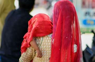 Bikaner: A mother covers child with a cloth on a hot summer day